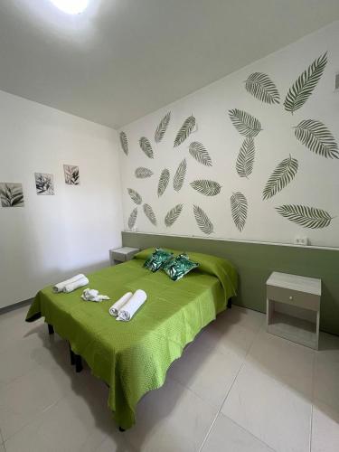 a bedroom with a green bed with towels on it at B&B Andromeda in Palmi