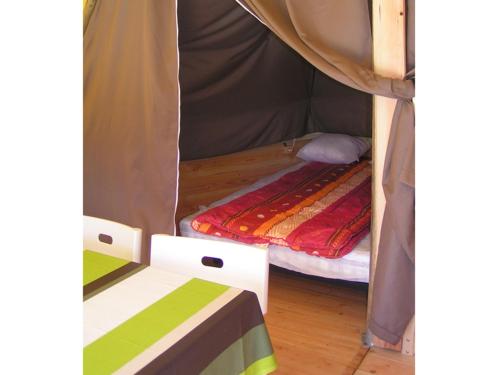 une chambre avec un lit dans une tente dans l'établissement BONNES VACANCES sur le CAMPING LE CLOS DES PINS, à Saint-Hilaire-de-Riez
