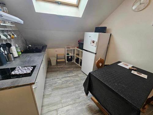 a small kitchen with a table and a refrigerator at Studios du Cèdre in Cuvilly