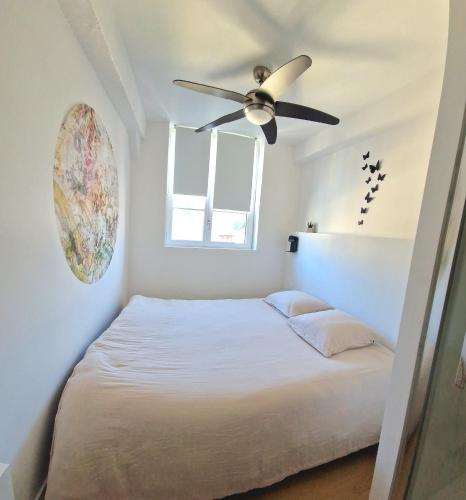 une chambre avec un lit avec un ventilateur de plafond dans l'établissement Les bons Enfants 5, à Rouen