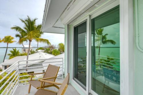 a porch with two chairs and a balcony with palm trees at Dock and Balcony Serene Big Coppitt Key Escape in Key West