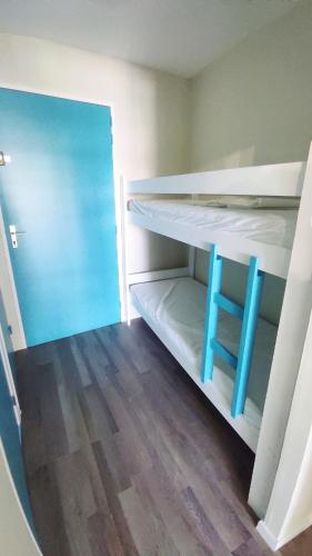 Cette chambre dispose de lits superposés et d'une chaise bleue. dans l'établissement Charmant studio en bord de mer, piscine, parking privé et wifi, à La Grande Motte