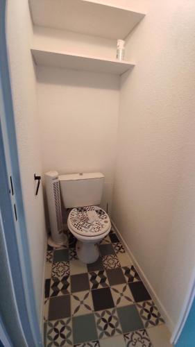 La salle de bains est pourvue de toilettes et de carrelage noir et blanc. dans l'établissement Charmant studio en bord de mer, piscine, parking privé et wifi, à La Grande Motte