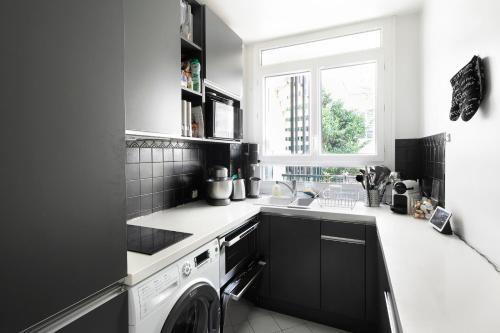 une cuisine en noir et blanc avec une machine à laver dans l'établissement Auguste Laurent - KP - Charming apartment with balcony 4 pers Paris 11, à Paris