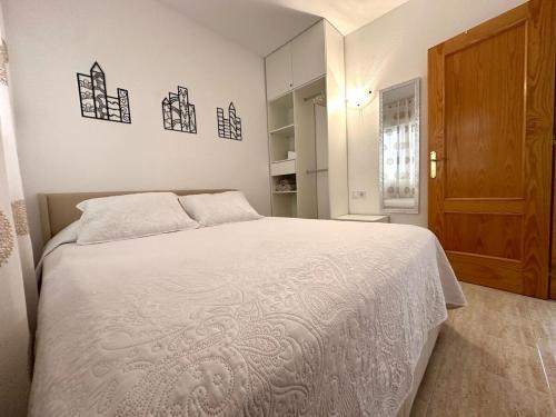 una camera da letto con un letto bianco e una porta di legno di Comfortable apartment with 2 bedrooms and Pool a Torrevieja