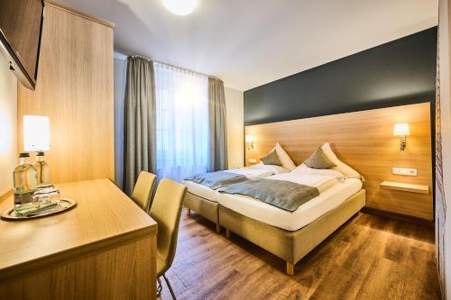 a hotel room with a bed and a desk at Hotel & Gasthaus DAS RÖHRL Straubing in Straubing