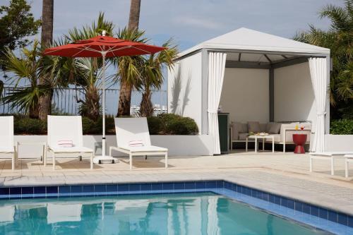 a pool with chairs and an umbrella next to a pavilion at Residence Inn by Marriott Miami Beach Surfside in Miami Beach