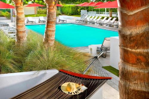 a hammock next to a swimming pool with palm trees at Residence Inn by Marriott Miami Beach Surfside in Miami Beach