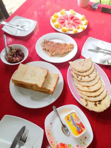 una mesa con platos de comida en una mesa roja en Near The Canal Homstay, en Sigiriya