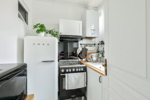 a small kitchen with a refrigerator and a stove at GuestReady - Serene Stay near Paris in Bois-Colombes
