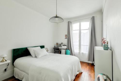 a white bedroom with a bed and a window at GuestReady - Serene Stay near Paris in Bois-Colombes