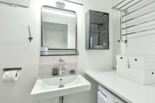 une salle de bain blanche avec un lavabo et un miroir dans l'établissement GuestReady - Serene Stay near Paris, à Bois-Colombes