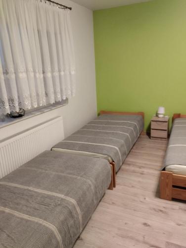 three beds in a room with green walls and a window at Agroturystyka u Pawła i Asi in Kobyla Góra