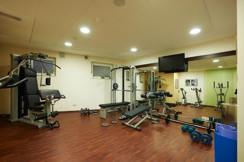 a gym with several machines and a flat screen tv at Familienhotel Maria in Obereggen
