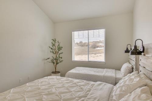 a white bedroom with two beds and a window at 5 Mi to Bear Lake State Park Home with Deck in Garden City