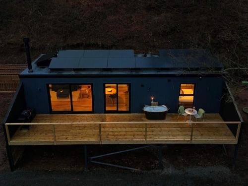 a tiny house sitting on a wooden deck at night at Heron - Luxurious Off-Grid Eco Cabin with River views in Market Drayton
