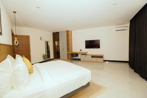 a bedroom with a large white bed and a desk at Noble Nook Boutique Hotel Abuja in Abuja