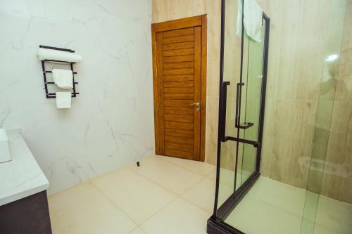 a bathroom with a shower and a glass door at Noble Nook Boutique Hotel Abuja in Abuja