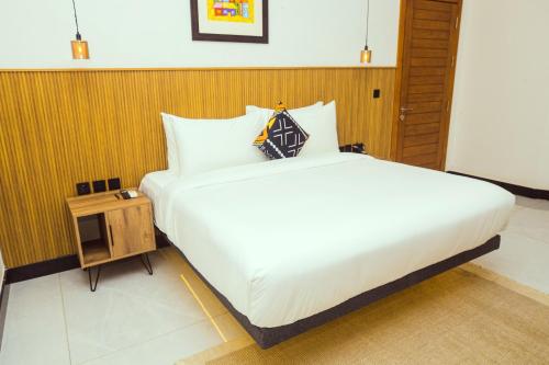 a bedroom with a large white bed and a wooden wall at Noble Nook Boutique Hotel Abuja in Abuja