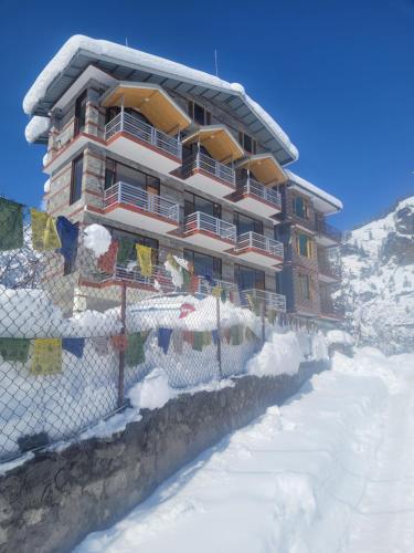 a building with a fence in the snow at Persimmon Farmstead in Manāli