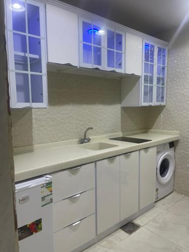 a kitchen with a sink and a washing machine at شقق قصر القمةالمخدومة in Al Qayşūmah