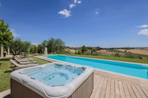 a hot tub on a deck next to a swimming pool at Villa Aurora in Trecastelli
