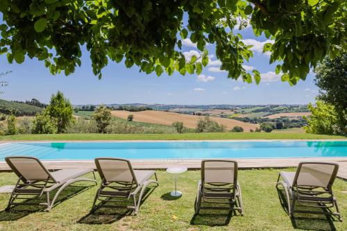 a group of chairs and a table next to a pool at Villa Aurora in Trecastelli