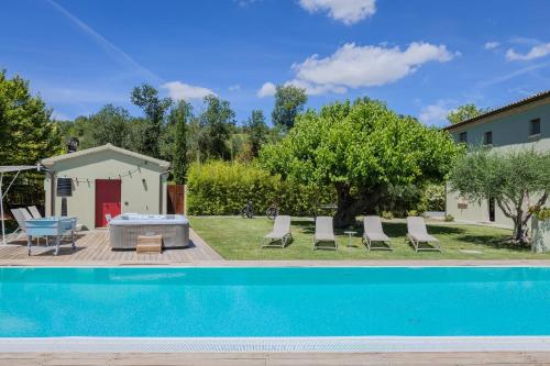 a pool in a yard with chairs and a house at Villa Aurora in Trecastelli