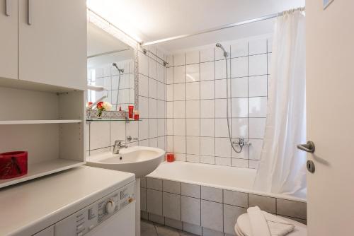 a white bathroom with a sink and a bath tub at Geana Apartments in Chania
