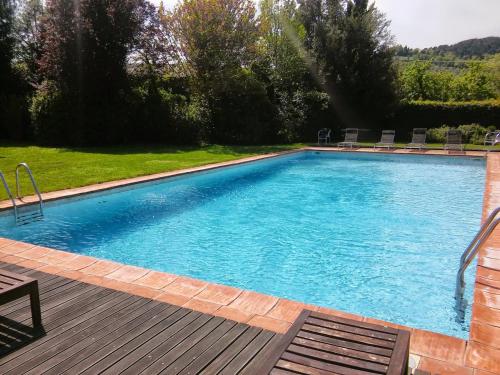 a large blue swimming pool with a wooden deck at Agriturismo Il Prato in Greve in Chianti