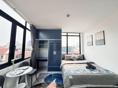 a bedroom with a bed and a table and some windows at The Little Hanoi - Cool Apartment - Lakeside in Hanoi