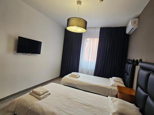 a hotel room with two beds and a flat screen tv at Meteor Central in Cluj-Napoca