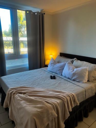a bedroom with a bed with white pillows and a window at Cómodo departamento con piscina en Los Ángeles in Los Ángeles