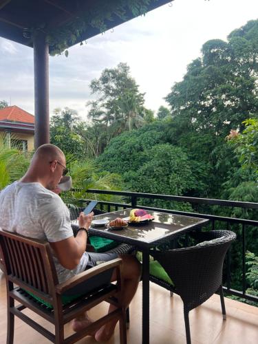 un hombre sentado en una mesa en un balcón en Central house, en Ubud