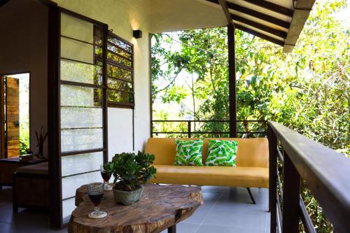 a porch with a yellow couch and a wooden table at Eco Lodge Glamping in Guatapé