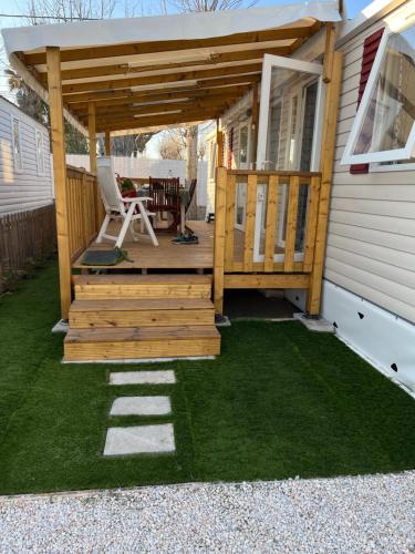 a wooden deck with a table and chairs on a house at Mobilhome bord de mer in Le Grau-dʼAgde