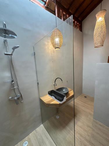 a bathroom with a shower with a sink and a lamp at Sunny Rose Bungalows Gili Air - Adults only in Gili Air