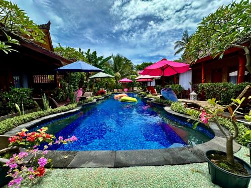 a swimming pool at a resort with umbrellas and flowers at Sunny Rose Bungalows Gili Air - Adults only in Gili Air