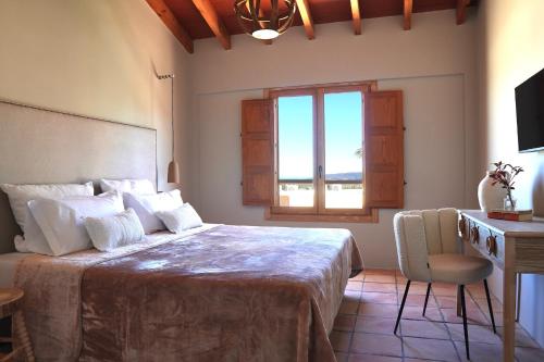 a bedroom with a bed with a desk and a window at Hotel Finca Olivar in Benissa