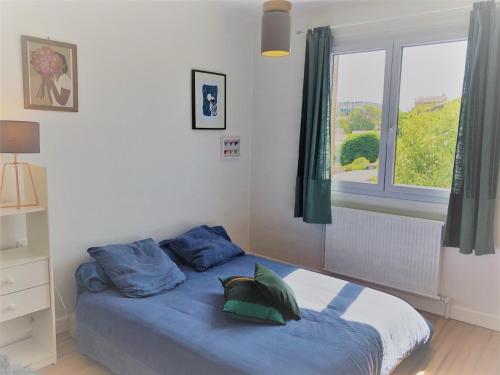 une chambre avec un lit avec des draps bleus et une fenêtre dans l'établissement Agréable T3 proche métro, tram & périph, à Toulouse