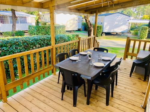 une table et des chaises sur une terrasse en bois dans l'établissement MOBIL HOME LUXUEUX de 3ch - CAMPING LA PIGNADE 4 Etoiles - RONCE-LES-BAINS - COTE ATLANTIQUE, à La Tremblade