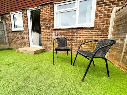 two chairs sitting on the grass in front of a house at 3 Bedroom House, WiFi & Free Parking in Chatham