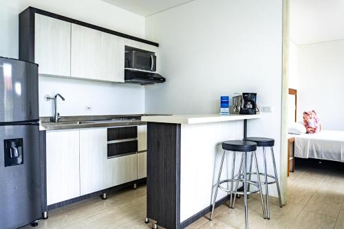 a kitchen with a sink and a counter with stools at Hotel Santorini in Guatapé