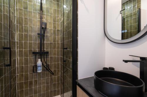 La salle de bains est pourvue d'un lavabo noir et d'une douche. dans l'établissement Cosy 1BR, Newly Renovated - Clichy | By Airnest, à Clichy