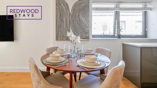 a dining room with a wooden table and chairs at QUALITY SERVICED APARTMENTS IN CAMBERLEY TOWN CENTRE, FREE WiFi, PERFECT FOR BUSINESS STAYS, FAMILIES, RELOCATIONS, EXTENDED STAYS, AND EMERGENCY ACCOMMODATION by REDWOOD STAYS in Camberley