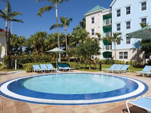 a swimming pool with lounge chairs and a building at Beautiful resort 1BD condo with amazing resort amenities pool, kiddie pool, and more in Nassau