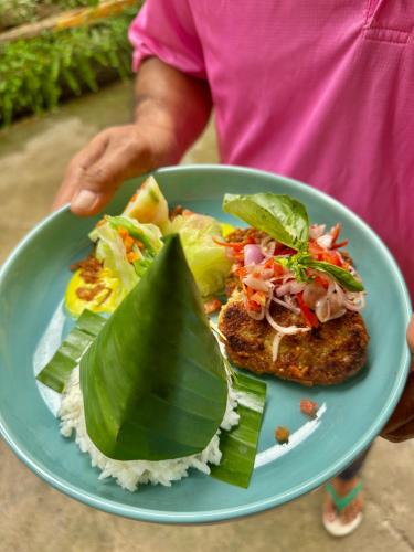 a person holding a blue plate with food on it at Sunny Rose Bungalows Gili Air - Adults only in Gili Air
