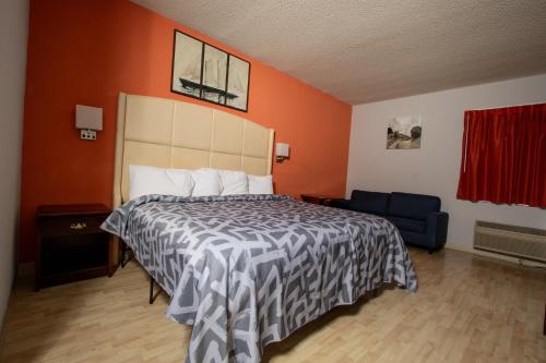 a bedroom with a bed and an orange wall at Scottish Inns & Suites - North Hershey in Harrisburg