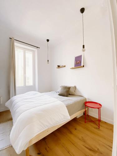 - une chambre blanche avec un lit et un tabouret rouge dans l'établissement L'appart Azur, 5 pers Joliette, à Marseille