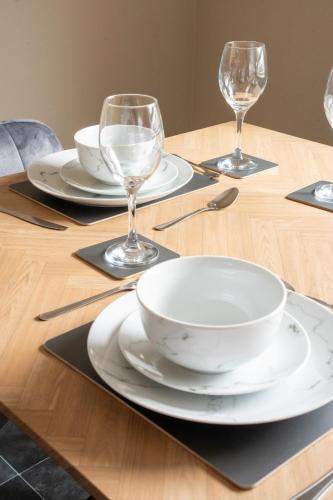 a wooden table with plates and wine glasses on it at Marina House in Bathgate